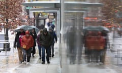 Tourists battle heavy rain and gusty winds with coats and umbrellas as they walk through downtown Seattle.