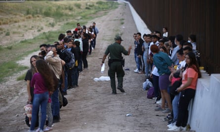 A group of migrants stand next to the border wall in Eagle Pass, Texas.