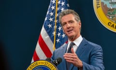 Man in suit in front of American flag and California state badge