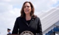 A woman wearing a black blazer speaks at a podium at an airport