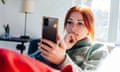 Young woman sitting on couch looking at mobile phone