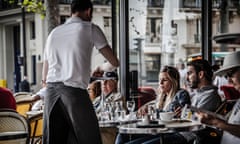 Waiter serving customers at  outdoor Parisian cafe