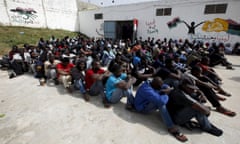 Illegal migrants sit in a detention center in Tripoli