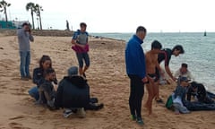 People tend to others sitting on a sandy beach near the shoreline