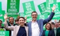 Carla Denyer and Adrian Ramsay wave in front of supporters who are holding green placards with the words 'Real hope. Real change. Vote Green.'