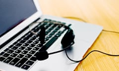 Black headset on a silver laptop with black keys.