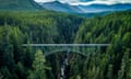 A bridge is surrounded by trees and mountains.