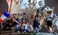 French leftwing campaigners cheer and wave flags on a public monument in Paris that is covered in graffiti.