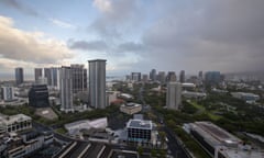 An aerial view of the city of Honolulu in Hawaii. Tall buildings and streets can be seen under a canopy of gray clouds.