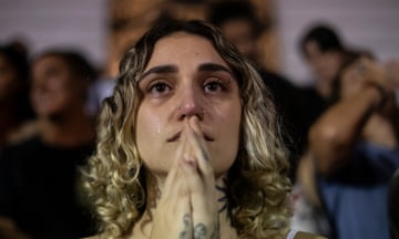 Kimberly Nobille cries with tattooed hands held to her mouth in prayer