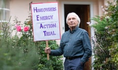 Colin Hines stands outside his house holding a placard for Homeowners Energy Action Trial