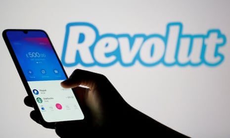 Woman holds smartphone with Revolut app in front of displayed Revolut logo 