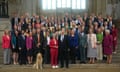 Rows of people in smart clothes pose for a picture inside parliament