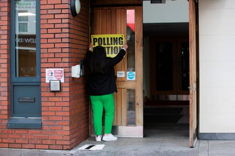 A member of the polling station team at the Agape Centre in south Belfast hangs a sign ahead of polling stations opening.