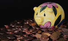 a yellow china piggy bank with a pattern of pink flowers and green leaves is seen resting on a pile of copper coins