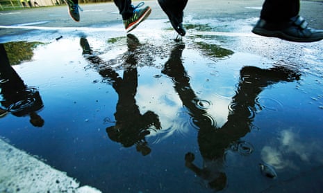 Children running in school playground, their legs reflected in rain puddle