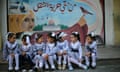 Palestinian schoolgirls sit in front of a mural on the first day of a new school year, at a United Nations-run school in Khan Younis in the southern Gaza Strip August 28, 2016