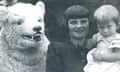 A woman holding a young child poses with a bear