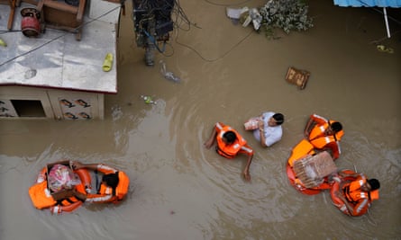 Disaster relief workers distributing aid to people affected by flooding in New Delhi, India, July 2023