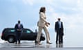 woman in white suit walks in front of men wearing suits