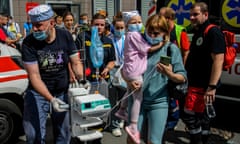 Medics carry a little girl and equipment at the site of a missile strike