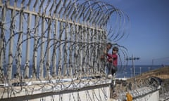 A boy is helped while climbing a fence in the area at the border of Morocco and the Spanish enclave of Ceuta in 2021. 