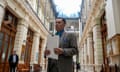 man wearing tweed suit and blue shirt holds papers