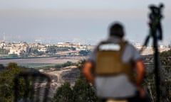 A journalist watches the skyline of the Gaza Strip from the southern Israeli city of Sderot  during Israeli bombardment on 18 October.