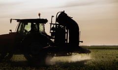 Tractor spraying pesticides over a green field