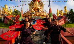 Novices use fans in martial arts in front of an elaborate golden statue