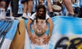 An Argentina fan touches a Lionel Messi flag.