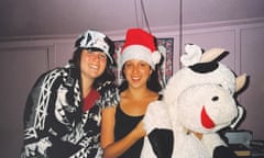 Two young women posing happily next to an oversized stuffed-toy cow