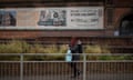 A woman walks by a sign promoting a levelling up scheme high behind her