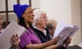 A woman in a blue hat sings from sheet music