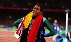 Cathy Freeman on the track with two flags draped around her neck