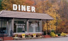 Exterior shot of the front of Phoenicia Diner in Phoenicia, New York state. Autumn foliage frames the box-like structure and its large, white 'Diner' sign.