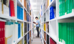 Chinese man holding book in library.