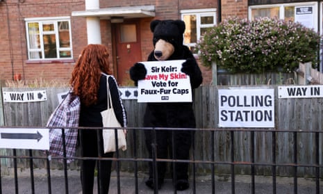 A Peta activist dressed as a bear holds a sign outside a polling station.