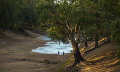 Men walk along the Darling Barka River, as a flow of water arrives from upstream