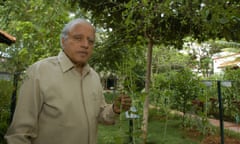 Dr MS Swaminathan holding a plant while standing among trees.