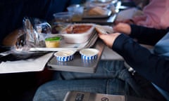 Passengers eating food on a plane.