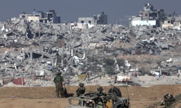 Israeli soldiers stand guard near the Israeli-Gaza border overlooking the Shujaiya neighbourhood near Gaza City