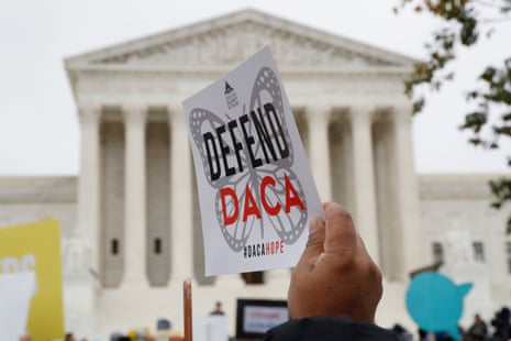 a person holds a sign that reads "Defend DACA"