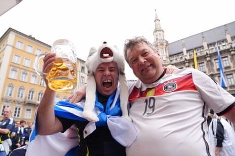 A Scotland fan holding a big glass of beer and a German fan.