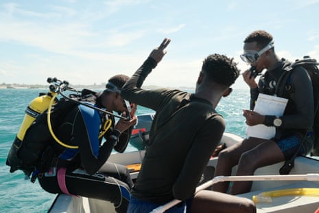 Three divers get ready to dive into the sea from a dinghy