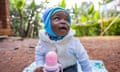 A smiling African baby with a bottle of milk