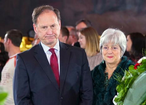 a balding man in a dark suit and red tie with a woman with short grey hair