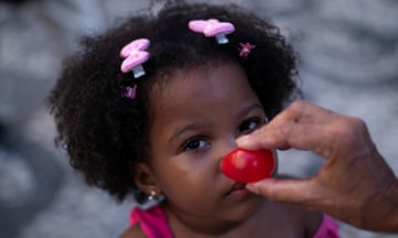 A clown nose is placed on a child's face during a protest opposing violence against women