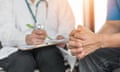 A doctor in a white coat takes notes from a patient