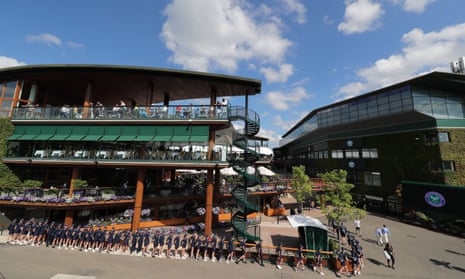 Ball boys and girls form a long line in front of a building at Wimbledon.